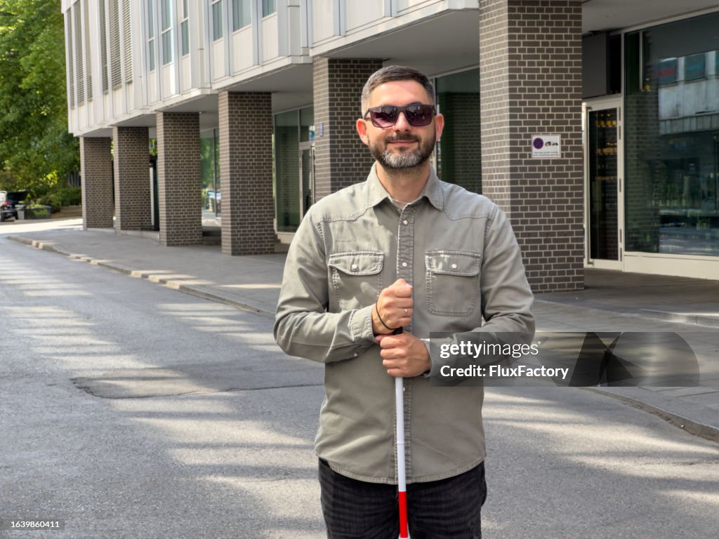Retrato de un hombre caucásico con discapacidad visual, sosteniendo un bastón