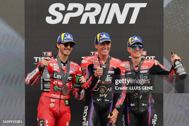 Winner Aprilia Spanish rider Aleix Espargaro celebrates on the podium with second placed Ducati Italian rider Francesco Bagnaia and third placed...