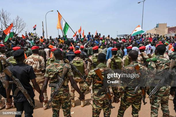 Nigerien soldiers stand guard as supporters of Niger's National Council of Safeguard of the Homeland protest outside the Niger and French airbase in...