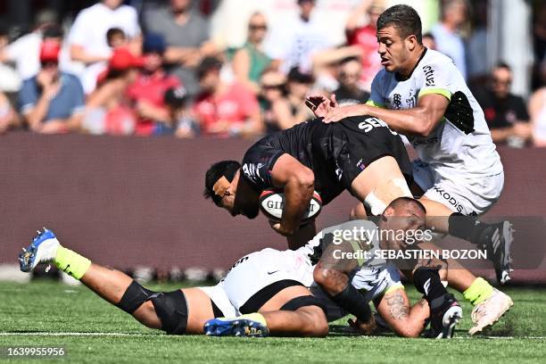 Oyonnax' French flanker Loic Credoz is tackled by Toulouse' Australian lock Piula Fa'asalele and Toulouse's French flanker Theo Ntamack during the...