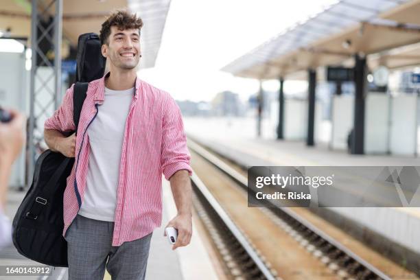 young man on a train station - guitar case stock pictures, royalty-free photos & images