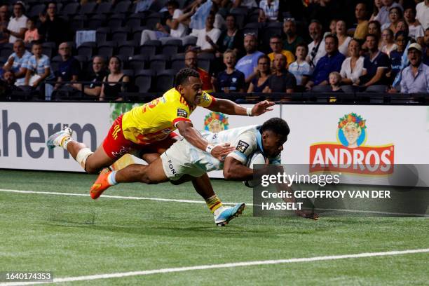 Racing92's Fijian wing Wame Naituvi dives to score a try as he is tackled by Perpignan's Fijian centre Alivereti Duguivalu during the French Top 14...