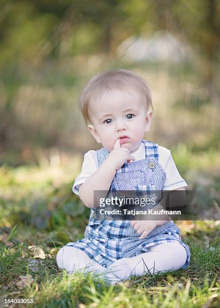 cute baby boy sitting in grass, lost in thought - lost sock stock pictures, royalty-free photos & images