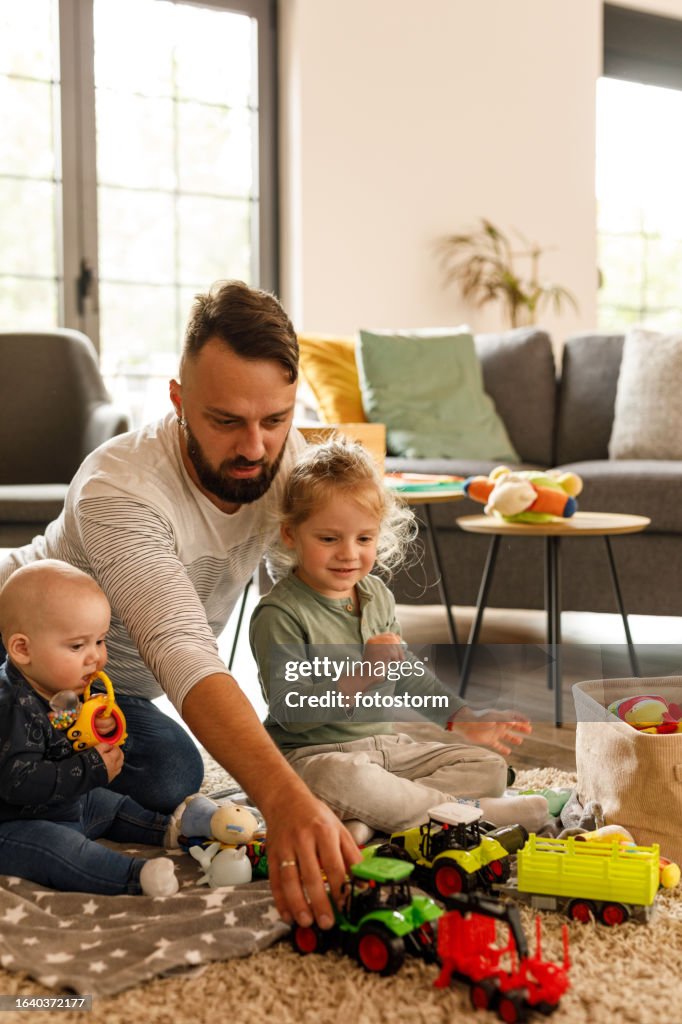 Man sitting on the floor, playing with his two little sons