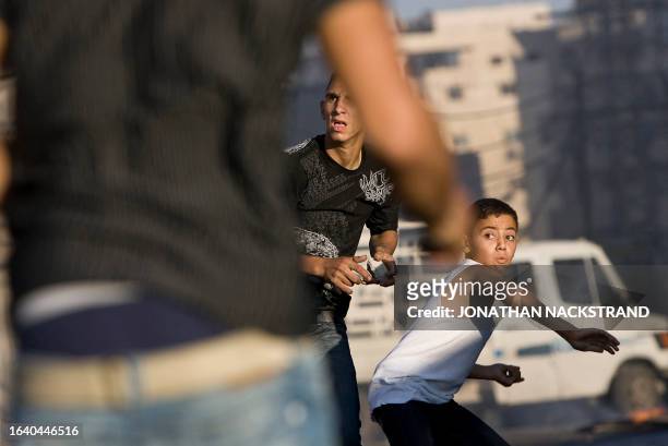 Palestinian youths hurl stones at Israeli forces during clashes on October 5, 2009 in the east Jerusalem Shuafat refugee camp. Police flooded into...