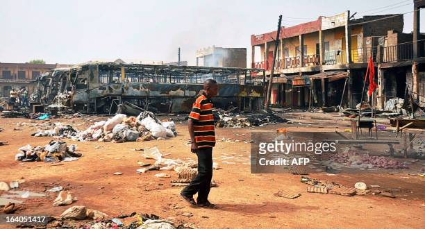 Man walks past burnt buses at New Road bus station in Sabon Gari district in northern Nigeria's largest city of Kano on March 19, 2013. Two suicide...