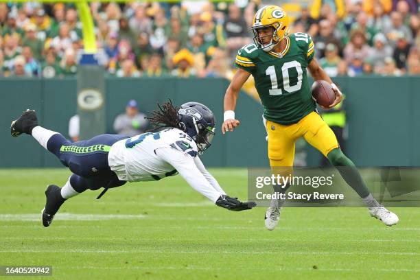 Jordan Love of the Green Bay Packers avoids a tackle by Myles Adams of the Seattle Seahawks in the first quarter of a preseason game at Lambeau Field...