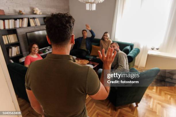 young man arriving to the pizza party and greeting his friends - the party arrivals stock pictures, royalty-free photos & images