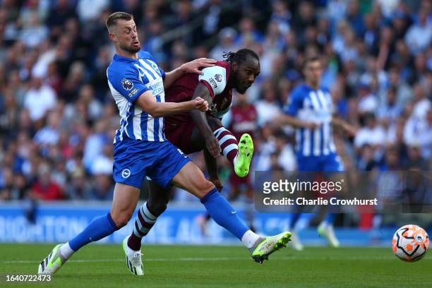 Michail Antonio of West Ham holds off Adam Webster of Brighton & Hove Albion to get his shot away during the Premier League match between Brighton &...
