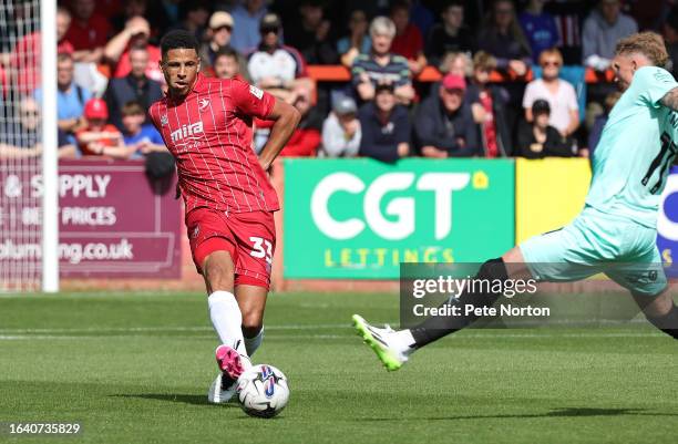 Curtis Davies of Cheltenham Town plays the ball past Mitch Pinnock of Northampton Town during the Sky Bet League One match between Cheltenham Town...