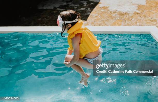 a child 'cannonballs' into an outdoor swimming pool - swimming pool stock pictures, royalty-free photos & images