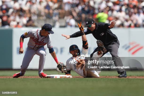 Davis of the San Francisco Giants reacts after hitting a double ahead of a tag by Nicky Lopez of the Atlanta Braves at Oracle Park on August 26, 2023...