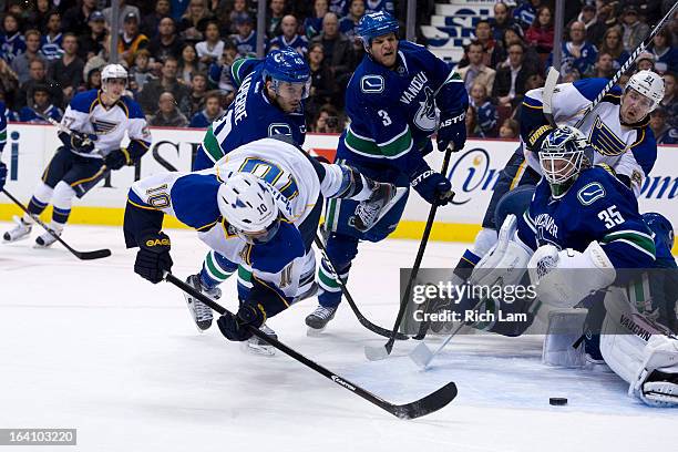 Andy McDonald of the St. Louis Blues flies through the air while trying to put a shot past goalie Cory Schneider of the Vancouver Canucks while Maxim...