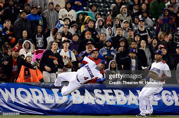 Miguel Tejada of the Dominican Republic dives to make a catch in foul territory in the seventh inning as Moises Sierra look on against Puerto Rico...