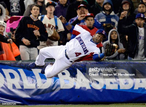 Miguel Tejada of the Dominican Republic dives to make a catch in foul territory in the seventh inning as Moises Sierra look on against Puerto Rico...