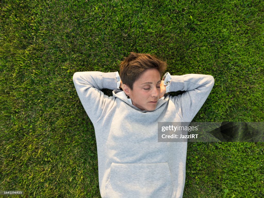 Adult woman lying down on the grass.
