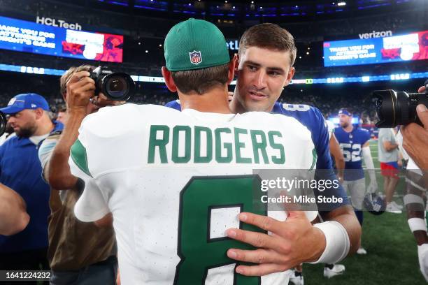 Daniel Jones of the New York Giants and Aaron Rodgers of the New York Jets hug following a preseason game at MetLife Stadium on August 26, 2023 in...