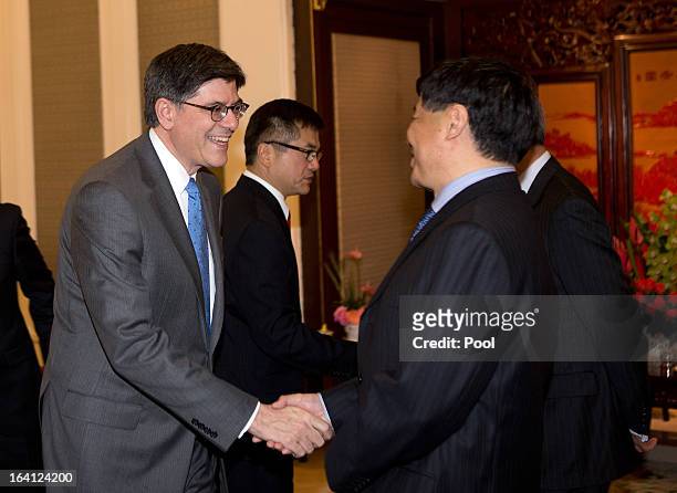 Treasury Secretary Jacob Lew, left, and U.S. Ambassador to China Gary Locke, center, are greeted by Chinese government officials before a meeting...