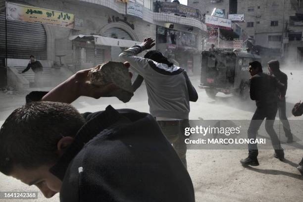 Palestinians pelt with stones a police jeep in the Shuafat refugee camp, north of Jerusalem, during the second day of unrest on February 9, 2010....