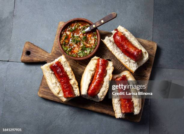 chilean food. traditional choripan with spicy pebre, chorizo sandwich with chorizo sausages and bread maraqueta. - roasted chile stock pictures, royalty-free photos & images