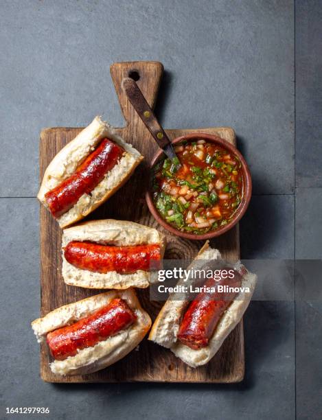 chilean food. traditional choripan with spicy pebre, chorizo sandwich with chorizo sausages and bread maraqueta. - chili pepper stockfoto's en -beelden