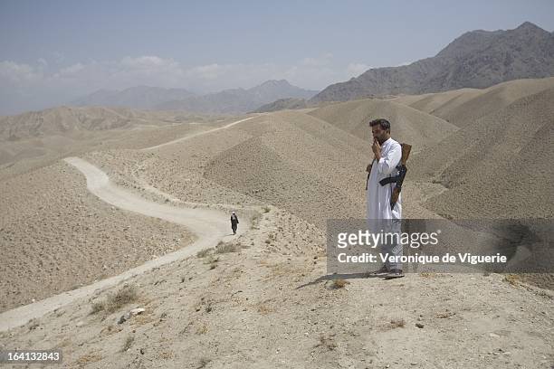 Afghan policemen look at the road leading to Spir Kundey, along which, on August 18 French soldiers on a patrol in Uzbeen Valley were ambushed by...