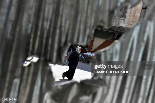 Syrian man is pictured through a hole in a metal sheet as he walks in Maarat al-Numan, in the northwestern province of Idlib, on March 20, 2013. The...