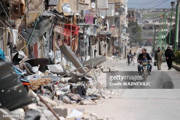 Syrians walk past damaged buildings in Maarat al-Numan, in the northwestern province of Idlib, on March 20, 2013. The number of Syrian refugees,...