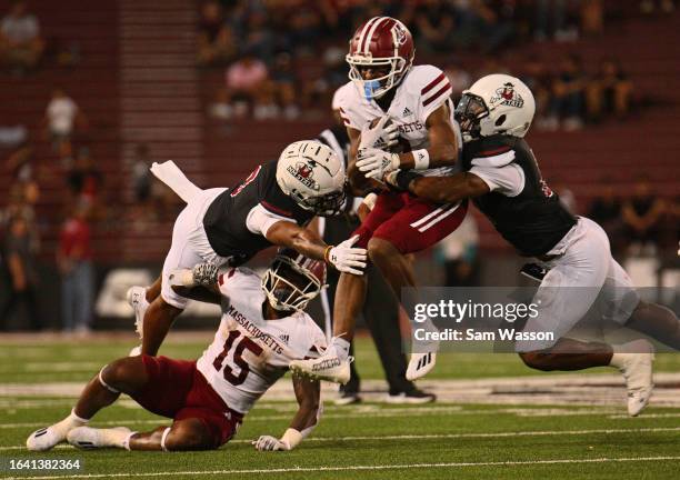 Wide receiver Mark Pope of the Massachusetts Minutemen is tackled by cornerback Andre Seldon and cornerback Josiah Charles of the New Mexico State...