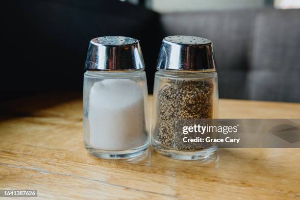 salt and pepper shakers on table at restaurant - service à condiments photos et images de collection
