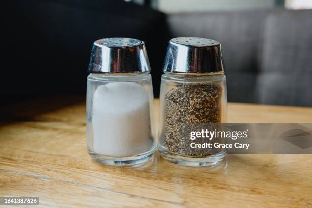 salt and pepper shakers on table at restaurant - salt shaker stock pictures, royalty-free photos & images