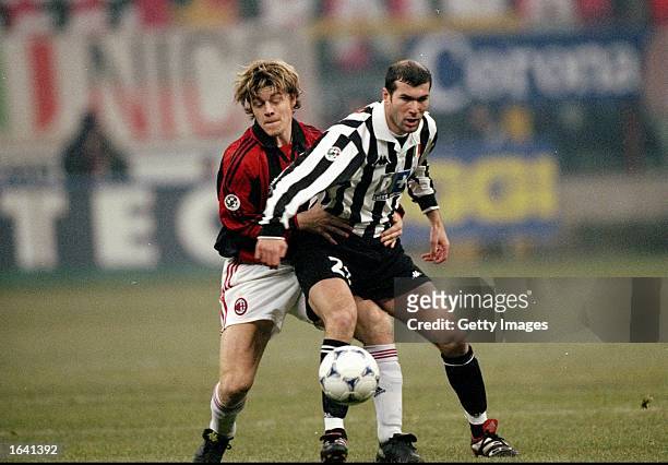 Zinedine Zidane of Juventus is challenged by Thomas Helveg of AC Milan during the Italian Serie A match at the San Siro Stadium in Milan, Italy. The...