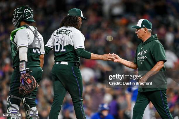 Bud Black of the Colorado Rockies walks to the mound to make a pitching change of Justin Lawrence as Elias Diaz looks on at Coors Field on September...