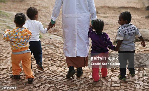 Woman walks with orphans at the AGOHELD orphanage, hospital, training center and school, founded by Abebech Gobena, on March 19, 2013 in Addis Ababa,...