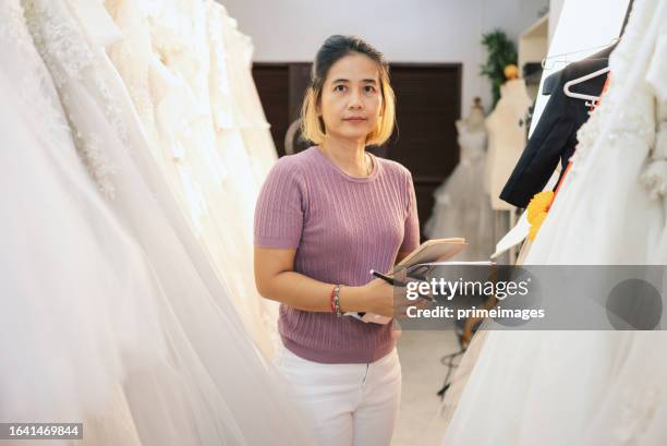 asian designer online e-commerce fashion store with female client trying on dress - bridal shop stock pictures, royalty-free photos & images