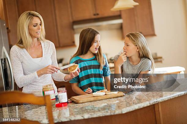 ältere frau benutzt erdnuss-butter auf brot - mother with daughters 12 16 stock-fotos und bilder