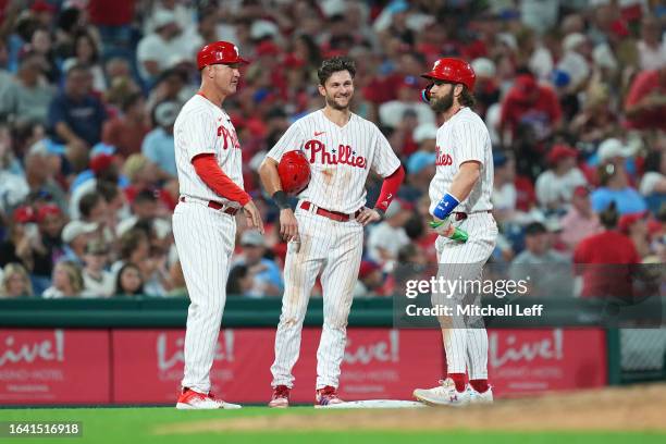 Dusty Wathan, Trea Turner and Bryce Harper of the Philadelphia Phillies look on against the St. Louis Cardinals at Citizens Bank Park on August 26,...