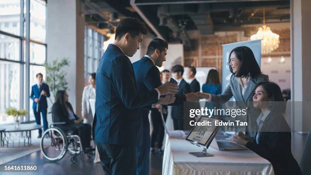 asian event participants guest registering at reception desk attending business conference seminar - exhibition stock pictures, royalty-free photos & images