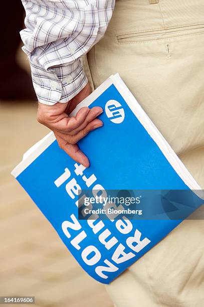 Shareholder carries a Hewlett-Packard Co. Annual report as he leaves the company's annual shareholders meeting in Mountain View, California, U.S., on...