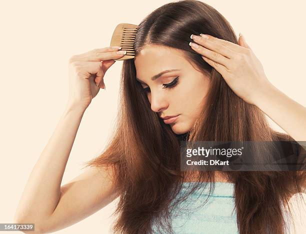 a young woman with beautiful long hair combing her locks - human hair stockfoto's en -beelden