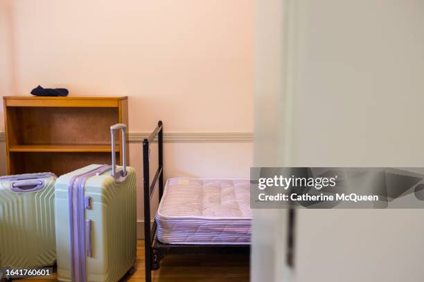view into student dorm room on move in day (suitcases, bed, bookshelf, hat in view) - eenpersoonsbed stockfoto's en -beelden
