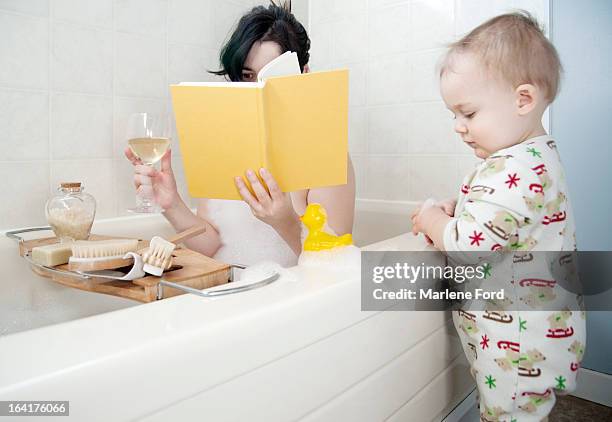 mother in bathtub with toddler beside tub - brown hair drink wine stock pictures, royalty-free photos & images