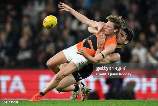 Lachie Whitfield of the Giants kicks whilst being tackled by George Hewett of the Blues during the round 24 AFL match between Carlton Blues and...