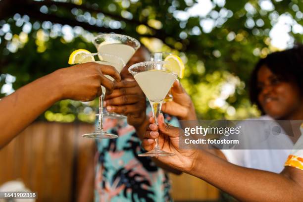 friends cheering with margarita cocktails during a garden party - summer cocktails garden party drinks stockfoto's en -beelden