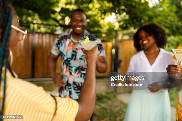 young woman raising a toast with her margarita cocktail during a garden party - summer cocktails garden party drinks stockfoto's en -beelden