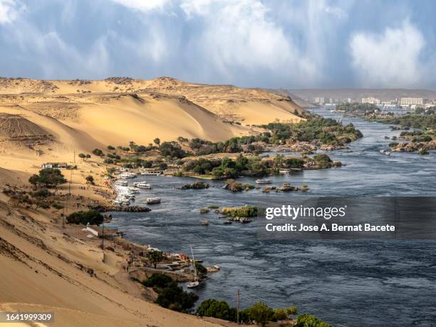 sandy beach on the nile river with tourist boats and people bathing in the river, nubian village, egypt. - アスワン ストックフォトと画像