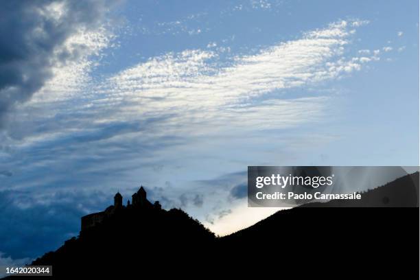 silhouette of säben abbey on tof of mountain at sunset - nonnenkloster stock-fotos und bilder