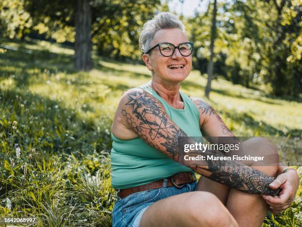 happy woman sitting in grass - old woman tattoos stock pictures, royalty-free photos & images