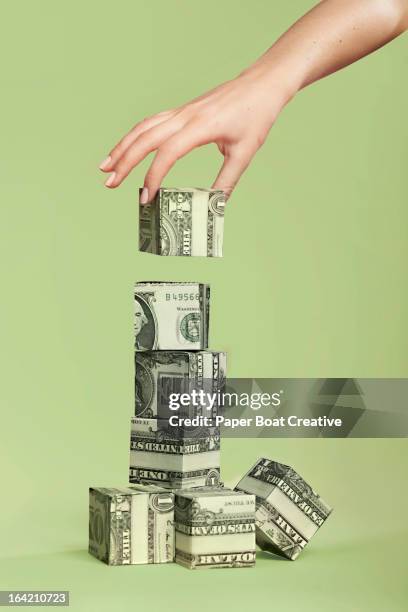 hand stacking up paper cubes made of dollar notes - concepts & topics foto e immagini stock