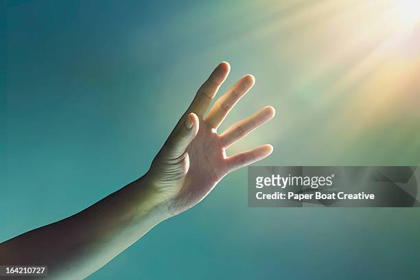 hand reaching towards glowing light from corner - religion stock-fotos und bilder